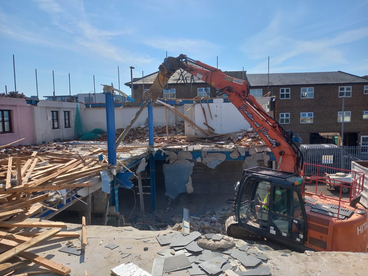 Excavator carrying out demolition of building